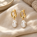 Lifestyle image of pearl and gold earrings styled on cream linen